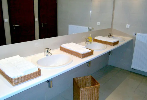 A commercial washroom vanity with three basins and mixers set into a long bench