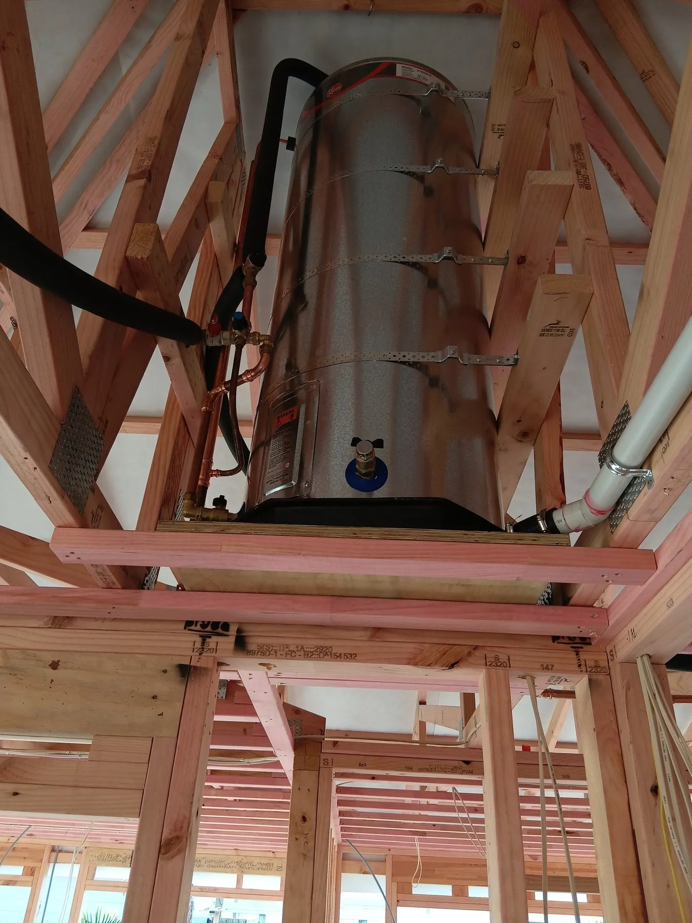 A Rheem hot water cylinder strapped into the roof space of a new build, with copper pipework run to it