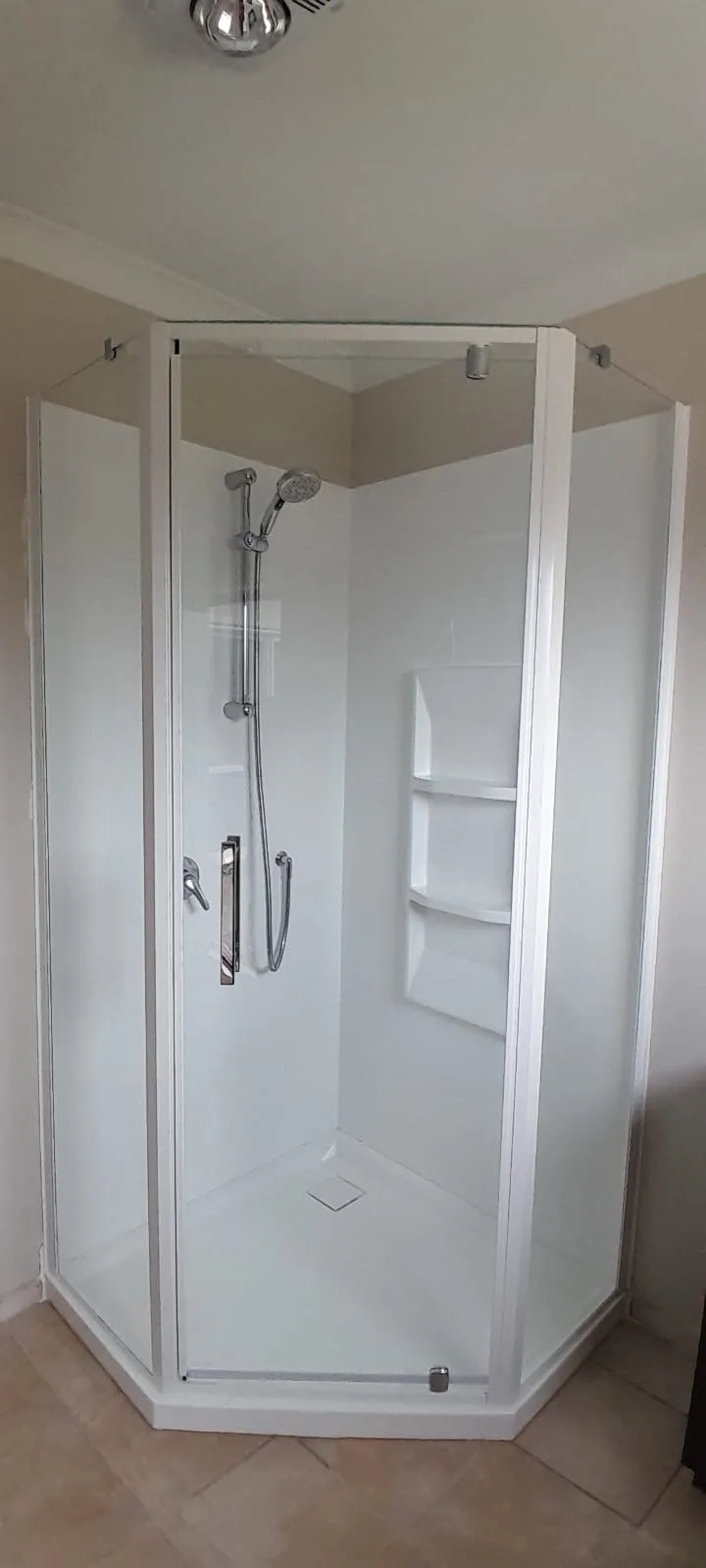 A newly installed corner shower with glass doors and chrome mixer in a Hawke's Bay home