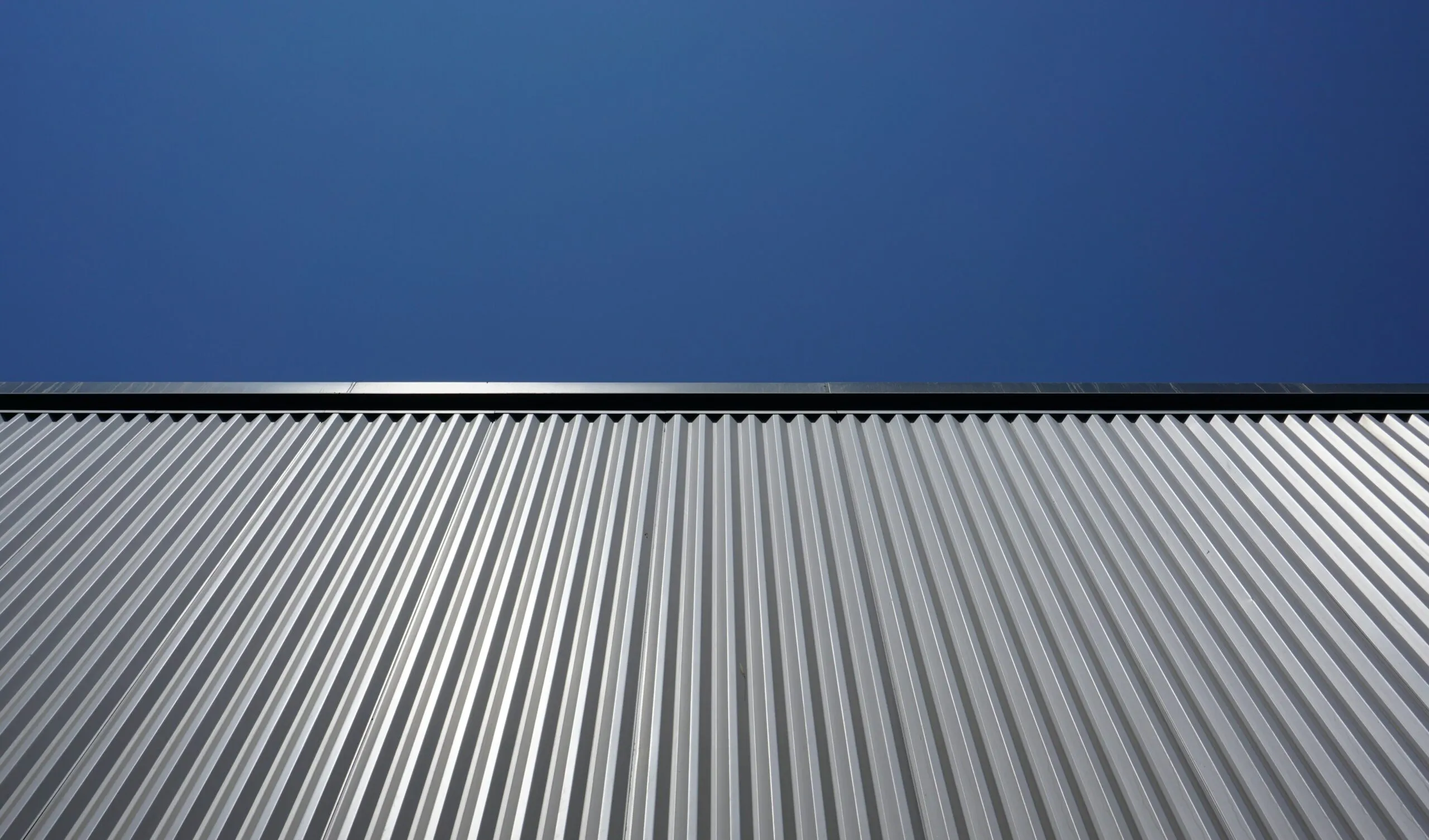 A corrugated metal roof running up to a clean ridge line against a deep blue sky